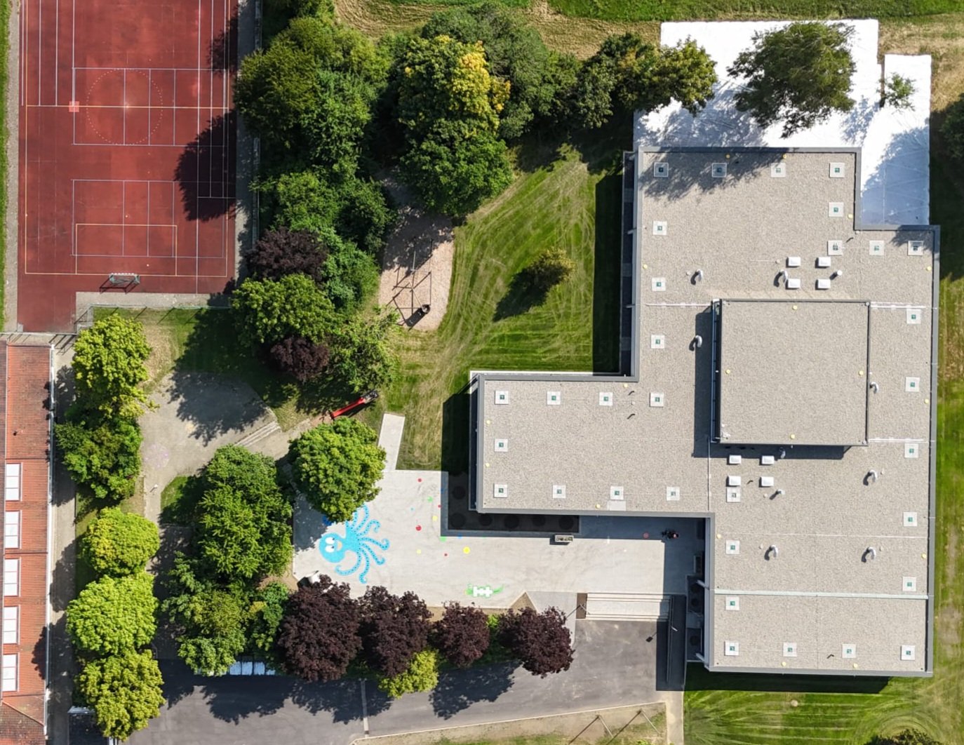Luftaufnahme der frisch sanierten Grundschule mit Sportplatz, Schulhof und Krake-Spielfeld